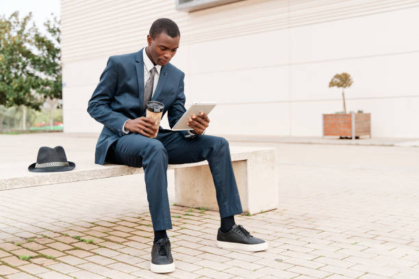 istock Young smart businessman using a digital tablet and analyse information on a bench in the city. Working outside and Mobile office business concept. 1393688551