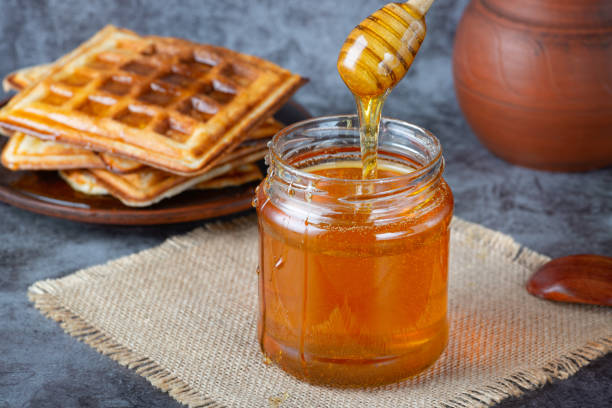 istock Honey in jar with honey dipper and belgian waffles 1393689107
