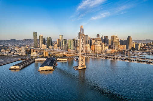 Aerial view on a clear day of the San Francisco skyline and Bay Bridge spanning the bay.