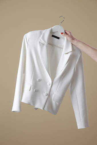 Woman holding white double breasted blazer on clothing hanger