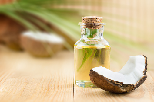 coconut oil and a slice of coconut on a wooden table
