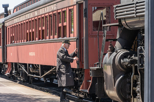 Strasburg, PA, USA - April 20,2022:  Train Conductor steps onto vintage train at the Strasburg Railroad station
