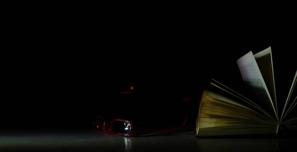 istock Open book, hardback book and specs on dark background. Back to school,education,reading. Copy space, negative space technique. 1393701993