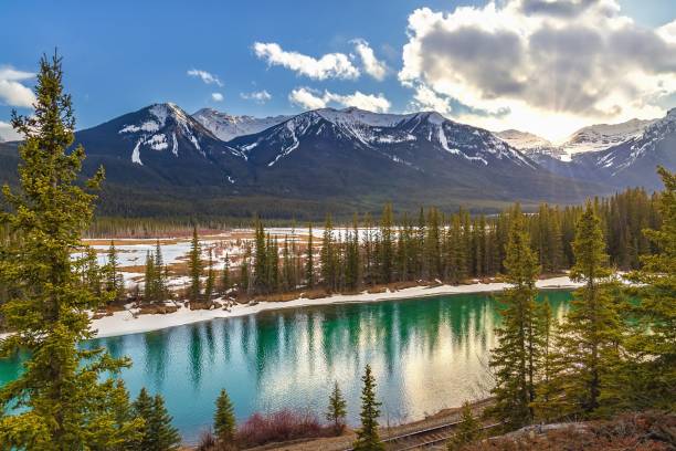 istock Sunshine Clouds Glowing Over Banff Mountains And River 1393707606