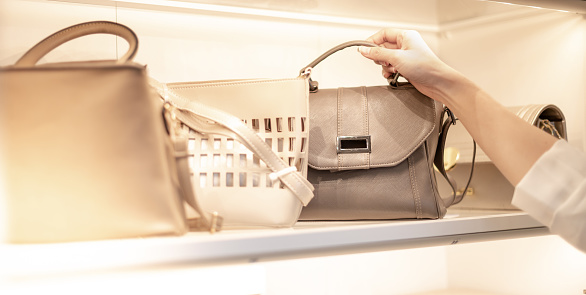 The female hand chooses a leather bag in a department store.