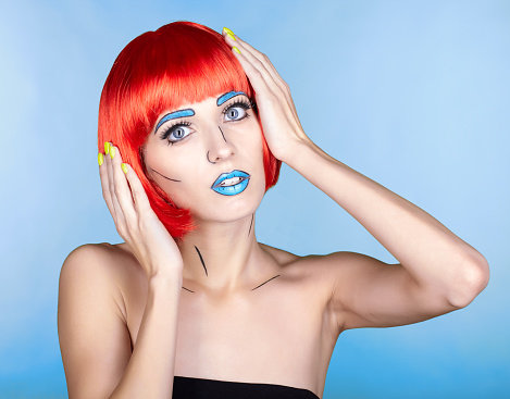 Portrait of young woman in comic  pop art make-up style. Female in red wig on blue background