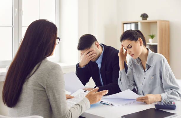 Couple getting very bad news from their lawyer, real estate agent or bank manager stock photo
