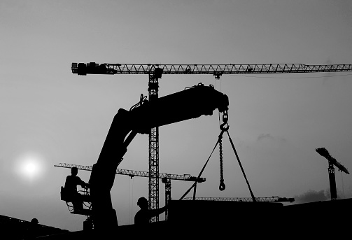Silhouette of worker and crane in construction site