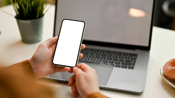 Female remote working at cafe, using smartphone and laptop