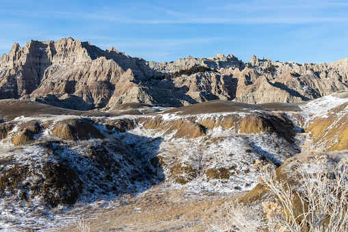 A light dusting of snow can be seen in the grass before some of the rock formations at Badlands National Park in South Dakota