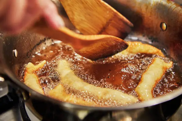 Bugnes, French donuts in boiling oil in saucepan.