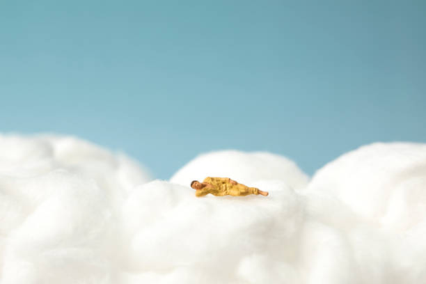 miniature man sleeping on the clouds miniature man sleeping on the clouds. cotton cloud stock pictures, royalty-free photos & images