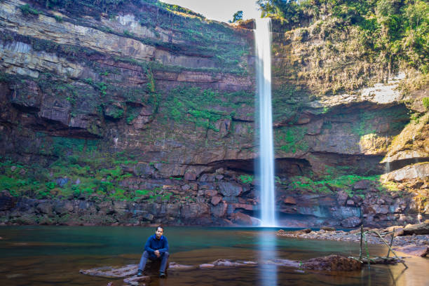 istock young man at waterfall falling streams from mountain top with reflection from different perspective 1393739628
