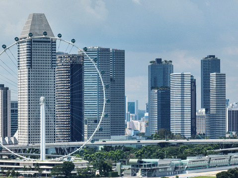 The Singapore Flyer Ferris Wheel seen during the day with financial district with crypto banks in the background. The Singapore Flyer Ferris Wheel is located in the middle of the city at Marina Bay.