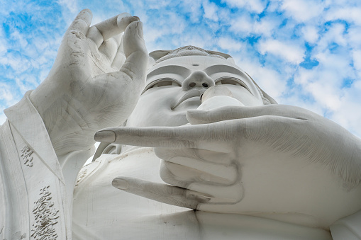Detail of Lady Buddha statue in a Buddhist temple and blue sky background in Danang, Vietnam. Close up, copy space