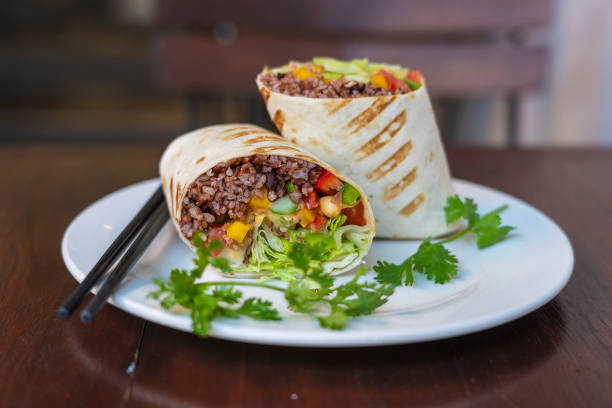 Vegan burrito. Sliced up raw food wrap with vegan ingredients on a plate stock photo