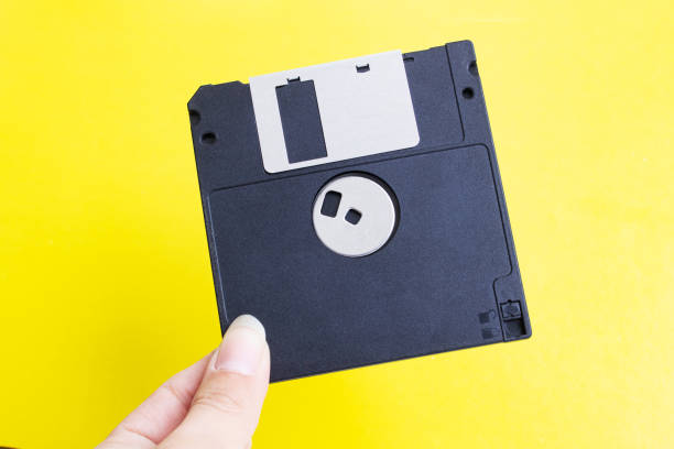 istock Floppy disk in hand on yellow background 1393741716