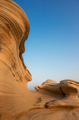 A lone rock, weathered by time, stands isolated in the vast expanse of the desert, embodying the arid solitude of its surroundings.