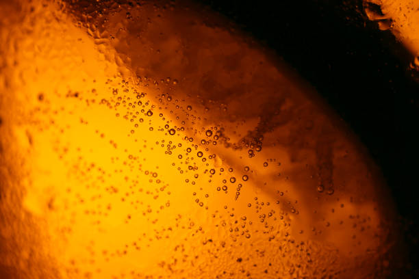 Amber back lighted frosty drink glass, with lime silhouette. Close up macro image texture. stock photo