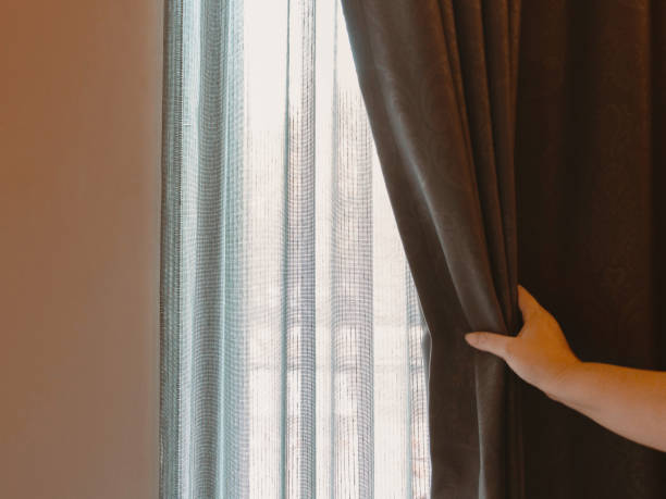 istock woman's hand opening brown luxurous curtain 1393749352