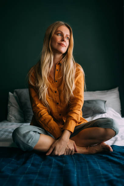 istock A Beautiful Blonde Female Casually Dressed Looking Away While Sitting On Her Bed 1393750116
