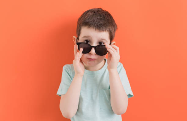 istock Caucasian boy in sunglasses orange background 1393753842
