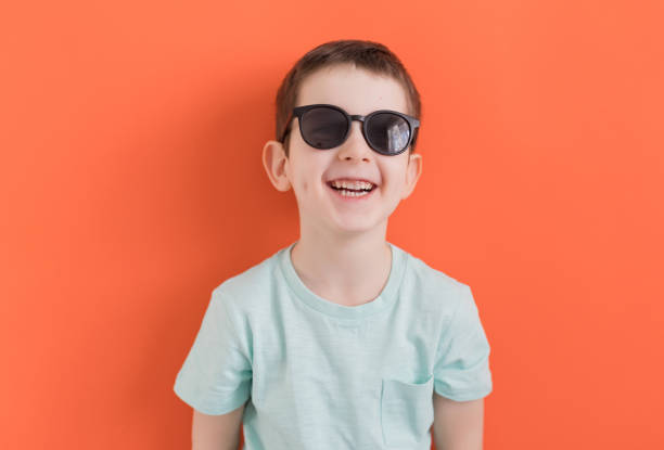 istock Caucasian boy in sunglasses orange background 1393753848