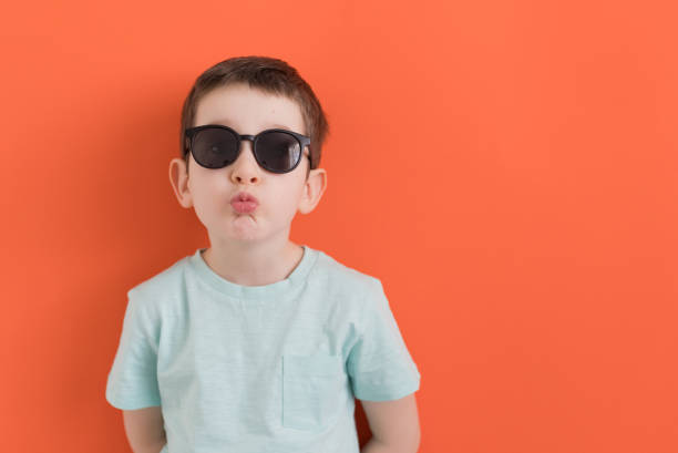 istock Caucasian boy in sunglasses orange background 1393753851