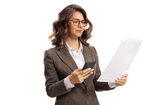Young woman with a mobile phone looking at a paper document isolated on white background