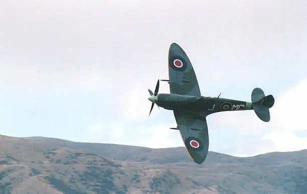 A spitfire flies low over airfield, banking towards the camera