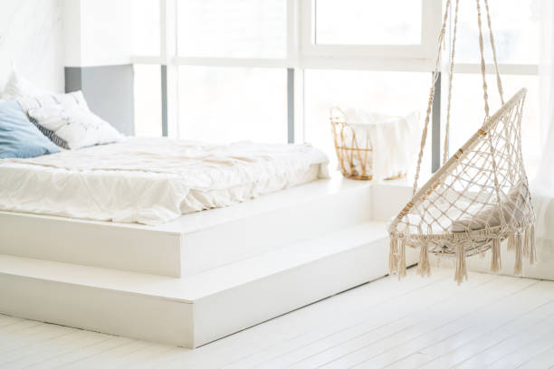 istock Bed with white linens in a bright bedroom with a large window 1393759925