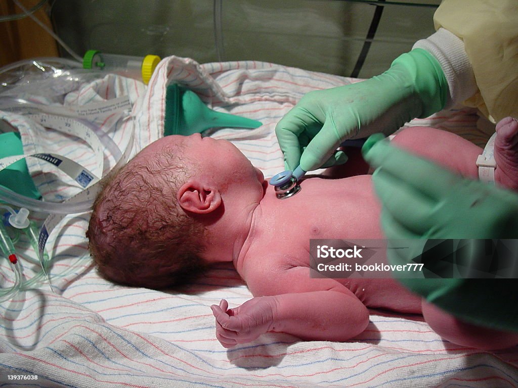 Brand new baby born in the hospital surrounded by nurses This is a newborn baby in the hospital with a nurse working on him. Baby - Human Age Stock Photo