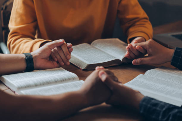 Christian family holding hands praying worship believe and seeking the blessings of God, fellowship, or bible study concept. They were reading the Bible and sharing the gospel. Christian family holding hands praying worship believe and seeking the blessings of God, fellowship, or bible study concept. They were reading the Bible and sharing the gospel. bible study group of people small group of people stock pictures, royalty-free photos & images