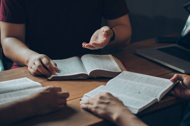 conceitos de estudo bíblico cristão. grupos de amigos cristãos leem e estudam a bíblia juntos em uma casa com luz da janela. seguidores estão estudando a palavra de deus nas igrejas. - holy book - fotografias e filmes do acervo