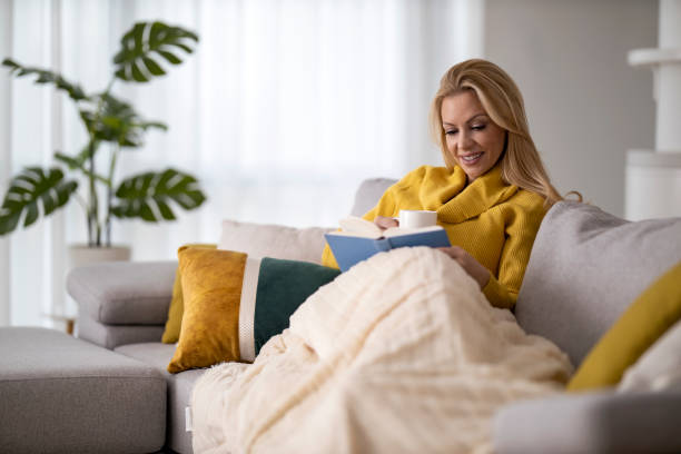 istock Woman reading book at home 1393761773