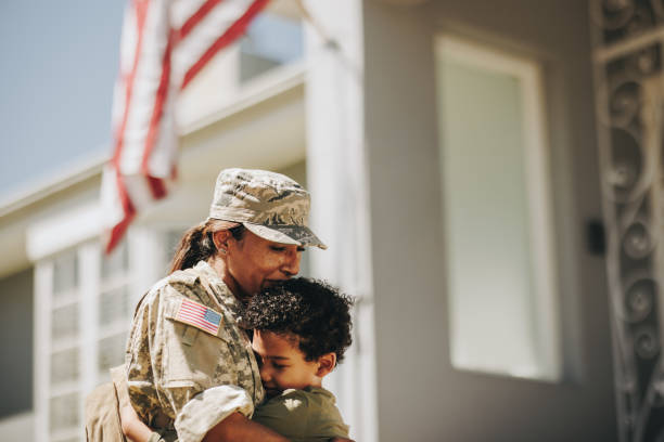 Mother and son reuniting after military deployment Mother and son reuniting after military deployment. Emotional mom embracing her son after returning home from the army. Patriotic female soldier receiving a warm welcome from her young child. military deployment photos stock pictures, royalty-free photos & images
