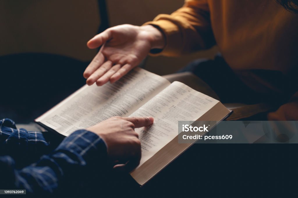 Male reading the Holy Bible by pointing to the character and sharing the gospel with a friend. Holy Bible study reading together in Sunday school.Studying the Word Of God With Friends. Religion Stock Photo