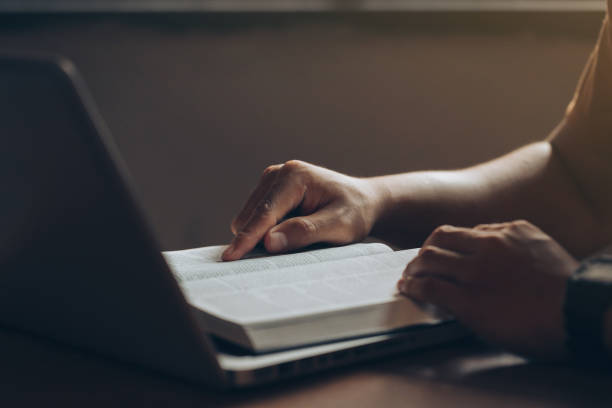 istock Young men concentrate on reading books with a laptop computer on the desk at home.Studying the Word Of God. bible study Concept 1393762177