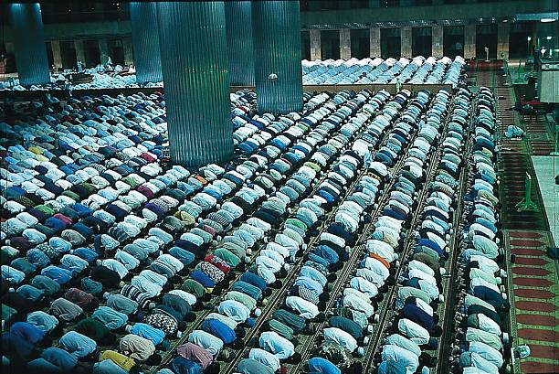 Salat in huge worship space with hundreds of people muslims praying (salat tarawih) in mosque istiqlal, jakarta, indonesia salah islamic prayer photos stock pictures, royalty-free photos & images