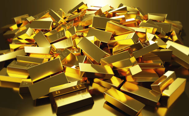 a large pile of gold bars in a row reflecting light. stock photo