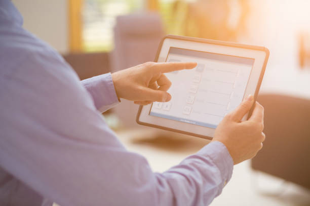 istock Man using smart home automation in living room with digital tablet 1393763777