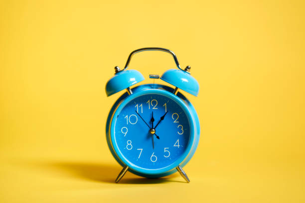 istock blue retro alarm clock on yellow background 1393764657