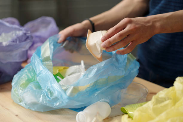 istock Hand of adolescent guy putting white small plastic yoghurt container into sack 1393764668