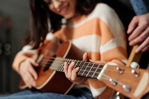 Mano del niño aprendiendo a tocar la guitarra mientras mantiene el dedo en una de las cuerdas photo