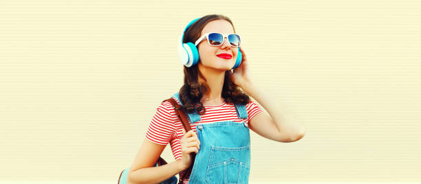 Portrait of happy smiling young woman with headphones listening to music on white background stock photo