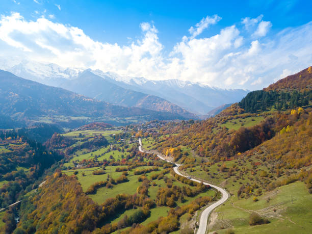 schöner, stimmungsvoller drohnenblick auf berge, schneebedeckte gipfel, serpentinen, landhäuser an einem sonnigen, hellen herbsttag, swanetien, georgien. - svaneti stock-fotos und bilder