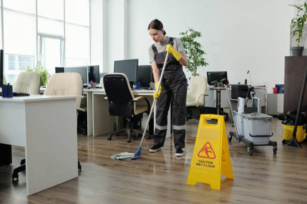 istock Young female cleaner in workwear using mop while cleaning floor in office 1393767111