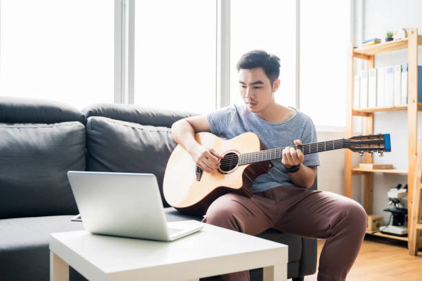 istock Working from home playing guitar learning online education video free time spending activity, self isolation quarantine lockdown staying safe in house living room protection from coronavirus covid-19 1393767168