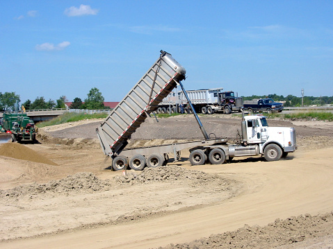 Dump truck unloading dirt at a road construction site