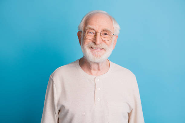 Photo portrait of old man in glasses smiling isolated on pastel blue colored background stock photo